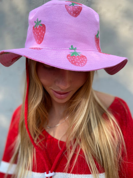 Strawberry hats that is pink and have a red string and toggle