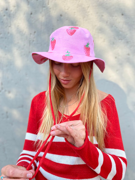 pink wide brimmed strawberry sunhat with red string and toggle