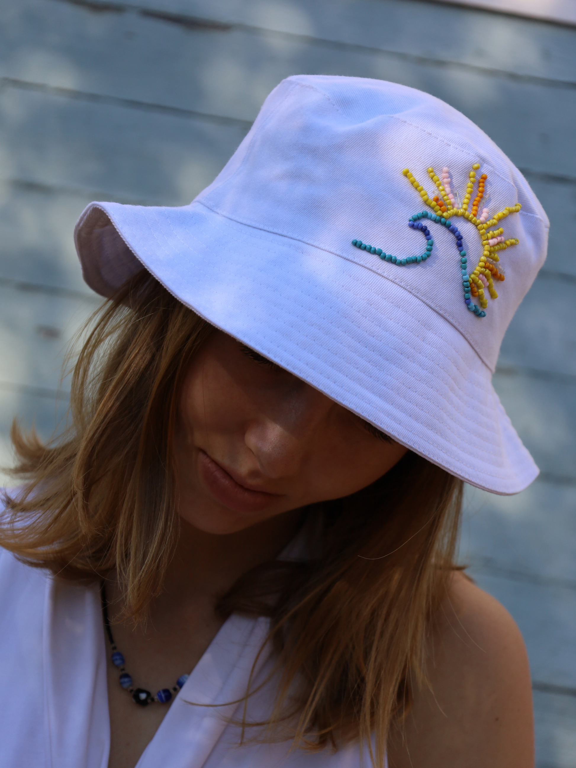 White bucket hat with beading of a sun and wave. Made in South Africa
