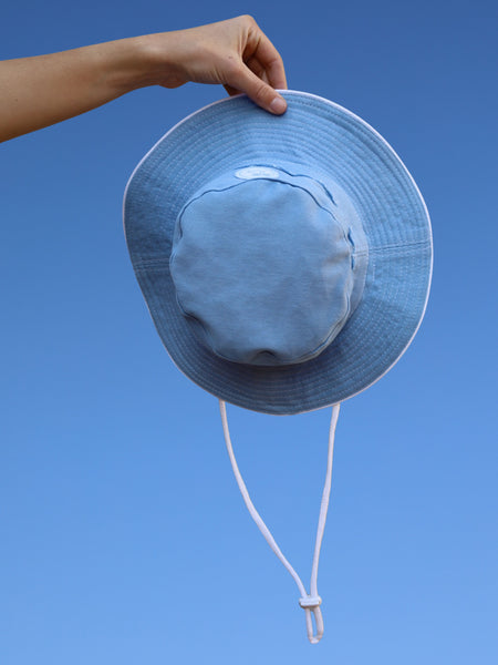 Blue sun hat held against a clear blue sky