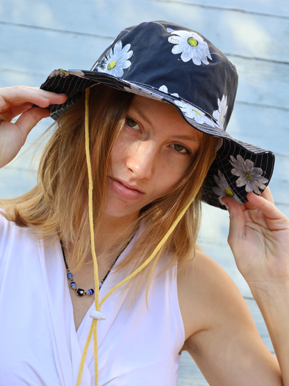 Woman wearing a navy fishermen hat with white daisy patterns. Made in South Africa
