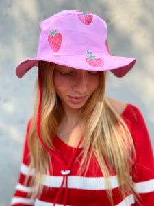 Strawberry hats that is pink and have a red string and toggle