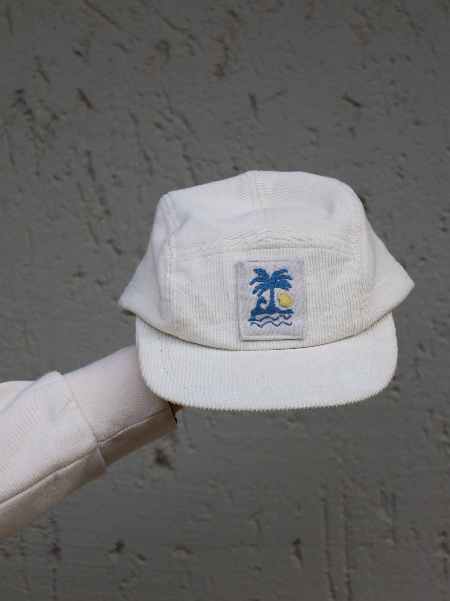 Cream corduroy cap with a embroidered palm tree and sun design