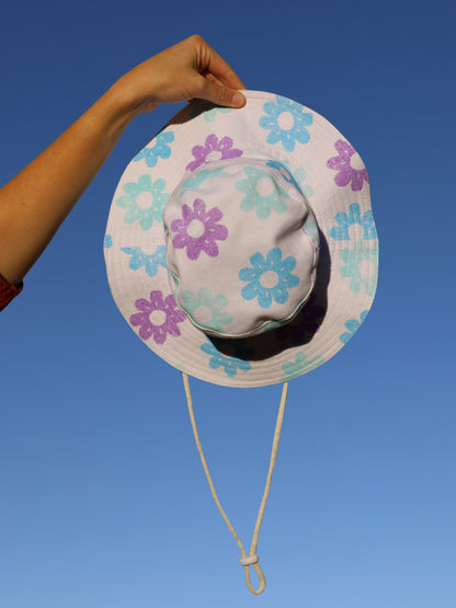 Colorful floral-patterned sun hat held against a clear blue sky
